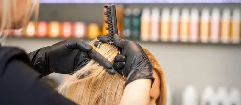 Hairdresser combing client's female hair before dyeing hair in a hair salon