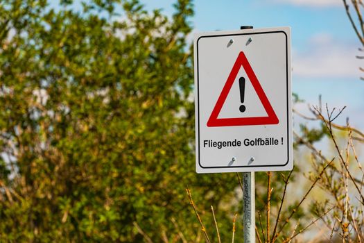 Caution flying golf balls as a warning sign on a golf course in Germany