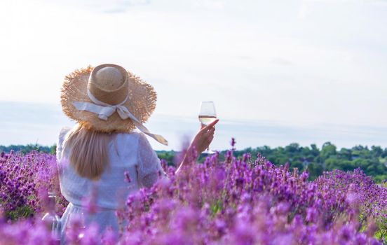 a girl in a lavender field pours wine into a glass. Relaxation. selective focus