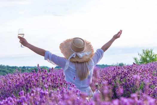 a girl in a lavender field pours wine into a glass. Relaxation. selective focus