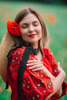Young pretty woman in vyshyvanka in poppies red field. Nature, flowers background. Lady in Ukrainian embroidered shirt. National traditional clothing. Culture concept. High quality photo