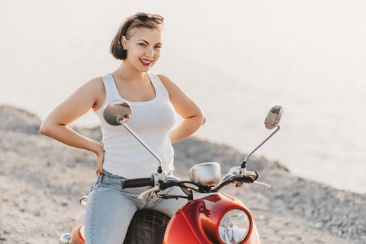 Young pretty woman's portrait. Girl sitting on red retro scooter at nature background. High quality photo