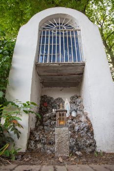 a chapel for prayers in the middle of the forest a figurine of St. Mary, a grotto for lighting candles a bench stands opposite, this is a place for solitude and reflection. High quality photo