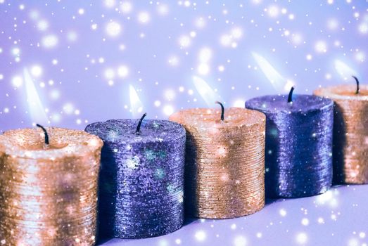 Winter, celebration and new years eve concept - Christmas candles and shiny snow on blue background, holiday season decoration