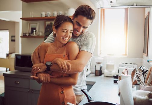Love, romance and fun couple hugging, cooking in a kitchen and sharing an intimate moment. Romantic boyfriend and girlfriend embracing, enjoying their relationship and being carefree together.
