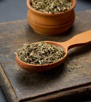 Dry basil in a wooden spoon on the table, seasoning