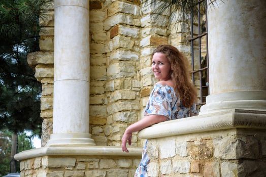 Portrait of young pretty woman on stairs near ancient historical building from stone and seashells.