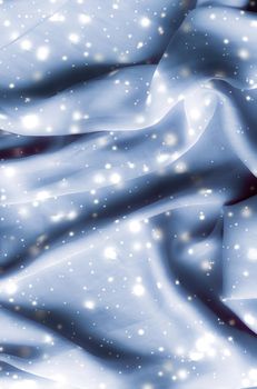 Winter fashion, shiny fabric and glamour style concept - Magic holiday blue soft silk flatlay background texture with glowing snow, luxury beauty abstract backdrop