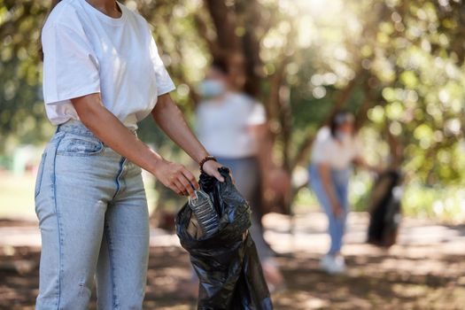 Volunteer, recycle and reduce global waste by picking up litter, dirt and garbage outdoors in a park. Closeup of young female NGO activist cleaning pollution from the environment for sustainability.