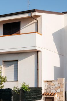 Typical white house facade part in italian city near the sea. Brown windows on white wall. Mediterranean village style architecture.