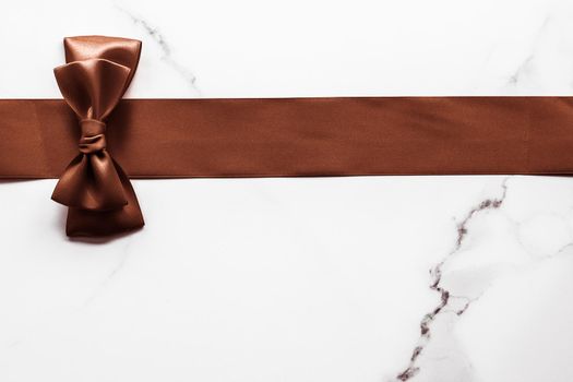 Holiday gift, decoration and sale promotion concept - Chocolate brown silk ribbon on marble background, flatlay