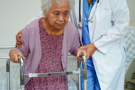 Doctor help Asian elderly woman disability patient walk with walker in nursing hospital, medical concept.