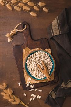 White beans in a ceramic bowl on a rustic kitchen countertop.