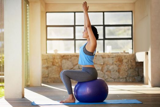 Facing her fitness goals head-on. a young woman working out with an exercise ball at home