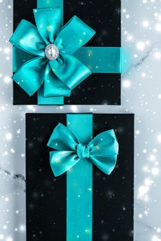 New Years Eve celebration, wrapped luxury boxes and cold season concept - Winter holiday gifts with emerald silk bow and glowing snow on frozen marble background, Christmas presents surprise