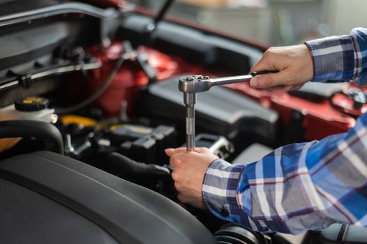 Female auto mechanic unscrewing a nut to replace a car spark plug