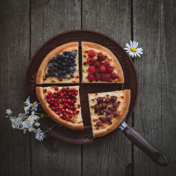 Homemade cheesecake Pie with berries and flowers On plate on Wooden Background