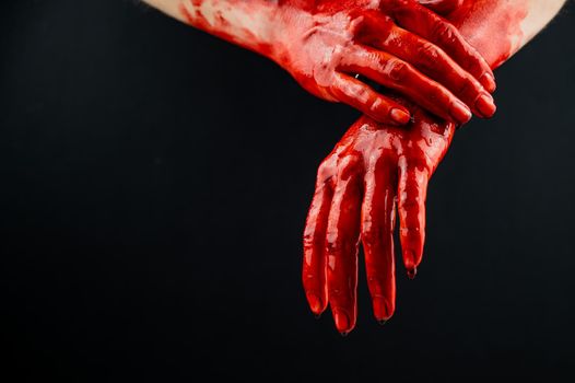 Women's hands in blood on a black background