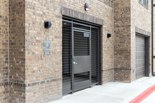 Entrance to the courtyard of a modern residential complex, lattice gates with a wicket and an entrance portal to the underground parking. Residents safety concept