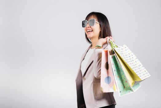 Happy woman with glasses confident shopper smiling holding online shopping bags colorful multicolor, Portrait excited Asian young female purchase studio shot isolated on white background, fashion sale