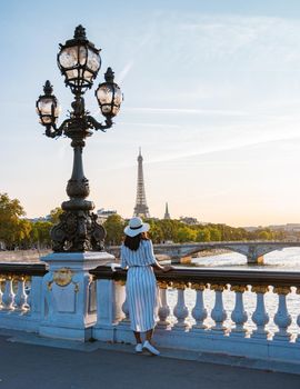 Young women with a hat viewing at the Eiffel tower from the Seine river, Alexander bridge Paris, view the famous landmark Alexander III bridge in Paris, the capital of France.