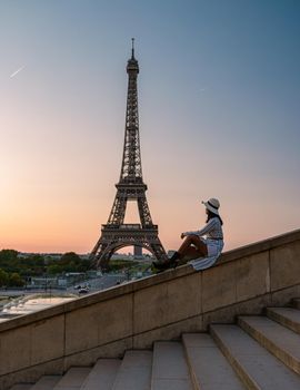 Young women with a hat visiting Eiffel tower at Sunrise in Paris France, Paris Eifel tower on a summer day in the city of Paris France