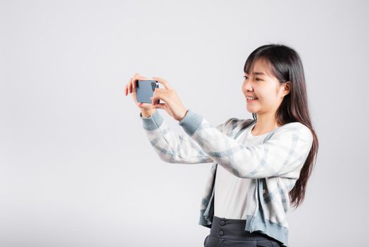 Woman excited holding smartphone to shooting selfie photo front camera studio shot isolated white background, happy young female smiling taking photography by mobile phone on mobile phone