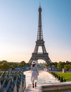 Young women with a hat visiting Eiffel tower at Sunrise in Paris France, Paris Eifel tower on a summer day in the city of Paris France