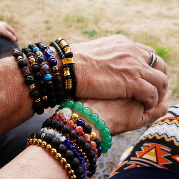 Senior couple holding hands. They are both fond of breaded bracelets. Pair look