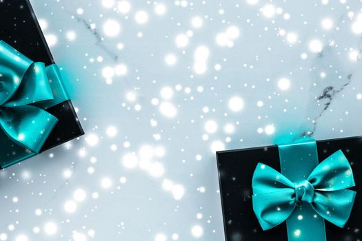 New Years Eve celebration, wrapped luxury boxes and cold season concept - Winter holiday gifts with emerald silk bow and glowing snow on frozen marble background, Christmas presents surprise