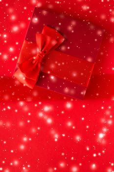 New Years Eve celebration, wrapped luxury boxes and Valentines Day card concept - Winter holiday gifts and glowing snow on red background, Christmas presents surprise