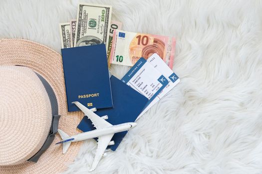 Travel accessories and items on a white background with a top view and copy space. Toy airplane in the clouds and a passport, money. Travel concept background for travel agency banner