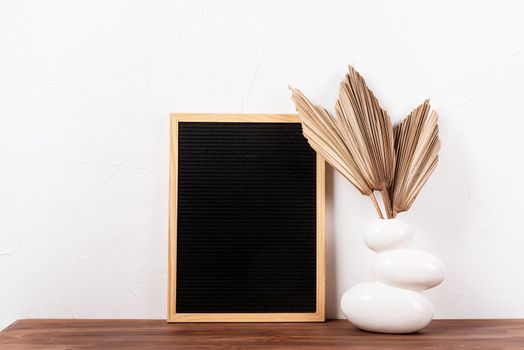 felt letter board with dry palm leaves on wooden table in a vase , mockup design