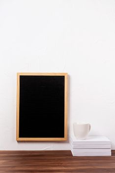 felt letter board mockup hanging on the wall with stack of books and coffee cup , mockup design