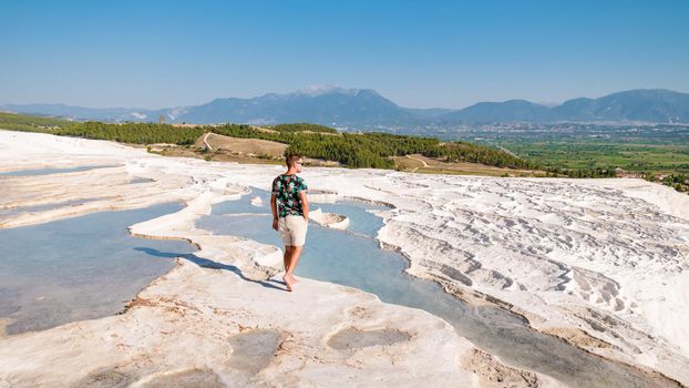 Natural travertine pools and terraces in Pamukkale. Cotton castle in southwestern Turkey, young men walking at the natural pool Pamukkale.