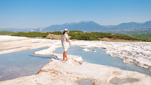Natural travertine pools and terraces in Pamukkale. Cotton castle in southwestern Turkey, girl in white dress with hat natural pool Pamukkale.