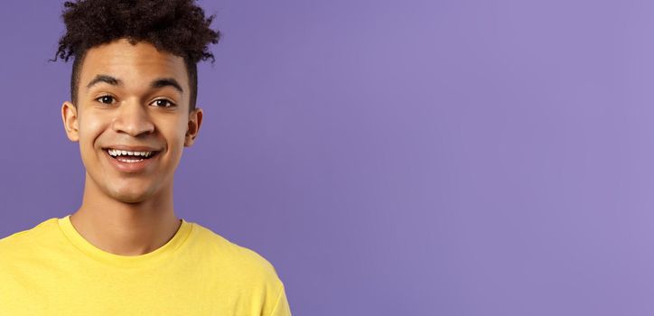 Close-up portrait of cheerful smiling man looking happy, express enthusiastic optimistic emotions, seeing something pleasant and interesting, standing purple background.