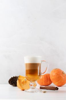 Autumn hot drinks. Pumpkin spice latte in a glass mug with cinnamon on light background with copy space