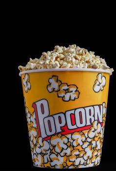 close-up of a popcorn container with colored letters on a black background