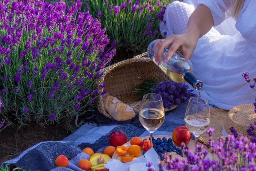 a girl in a lavender field pours wine into a glass. Relaxation. selective focus