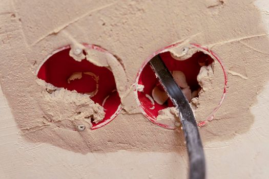 Installation of new electrical wiring, plastic sockets smeared with mortar and electrical wires for future sockets on a plastered wall, the concept of home renovation