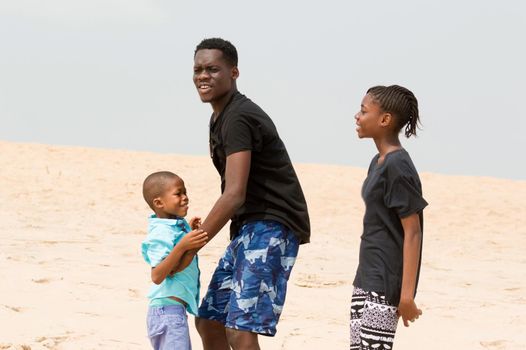 young man wanting to lift his little brother and little sister looks at them smiling.