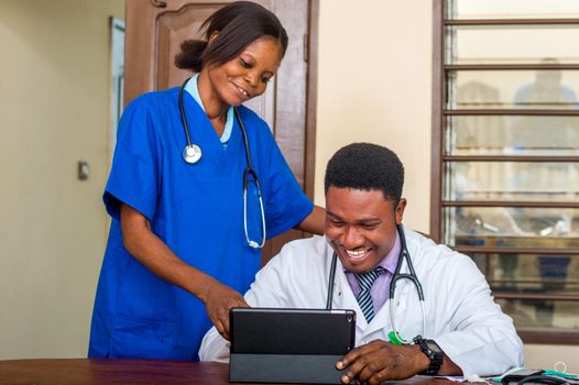 the smiling doctor explains working techniques to the nurse in his office.