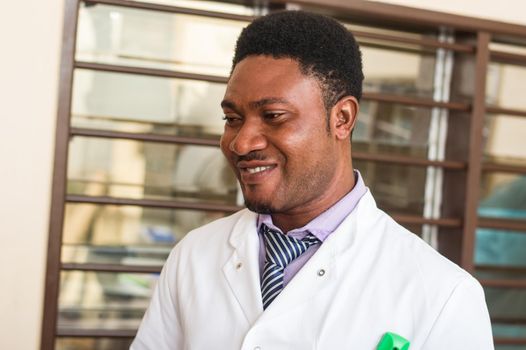 Smiling medical doctor in white coat standing in his office