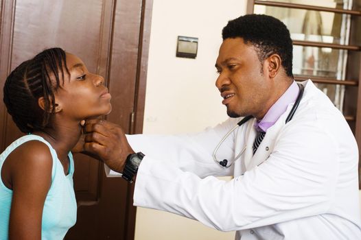 doctor examines a patient by touching her throat in her clinic.