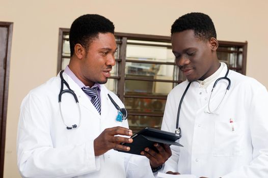 doctor and professor standing talking on a digital tablet at the hospital.