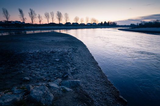 Sunrise by the river Drava. Closeup white stones. An idyllic sunrise in nature. Landscape photo of sunrise with sun the right upper corner, white stones in a front and a river in a middle. Croatia.