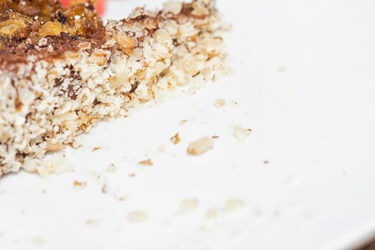 Close up view of a skice of brown, chocolate cake on a white plate. Chocolate crumbs can be seen on the plate.