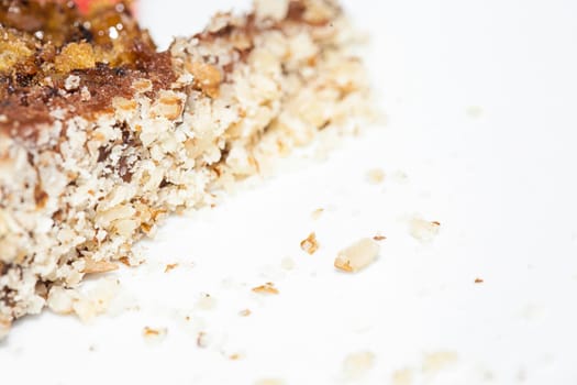 Close up view of a skice of brown, chocolate cake on a white plate. Chocolate crumbs can be seen on the plate.