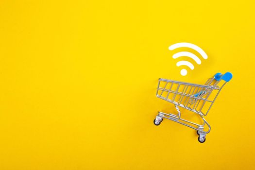 close-up of shopping trolley with wifi signal on yellow background with copy space
